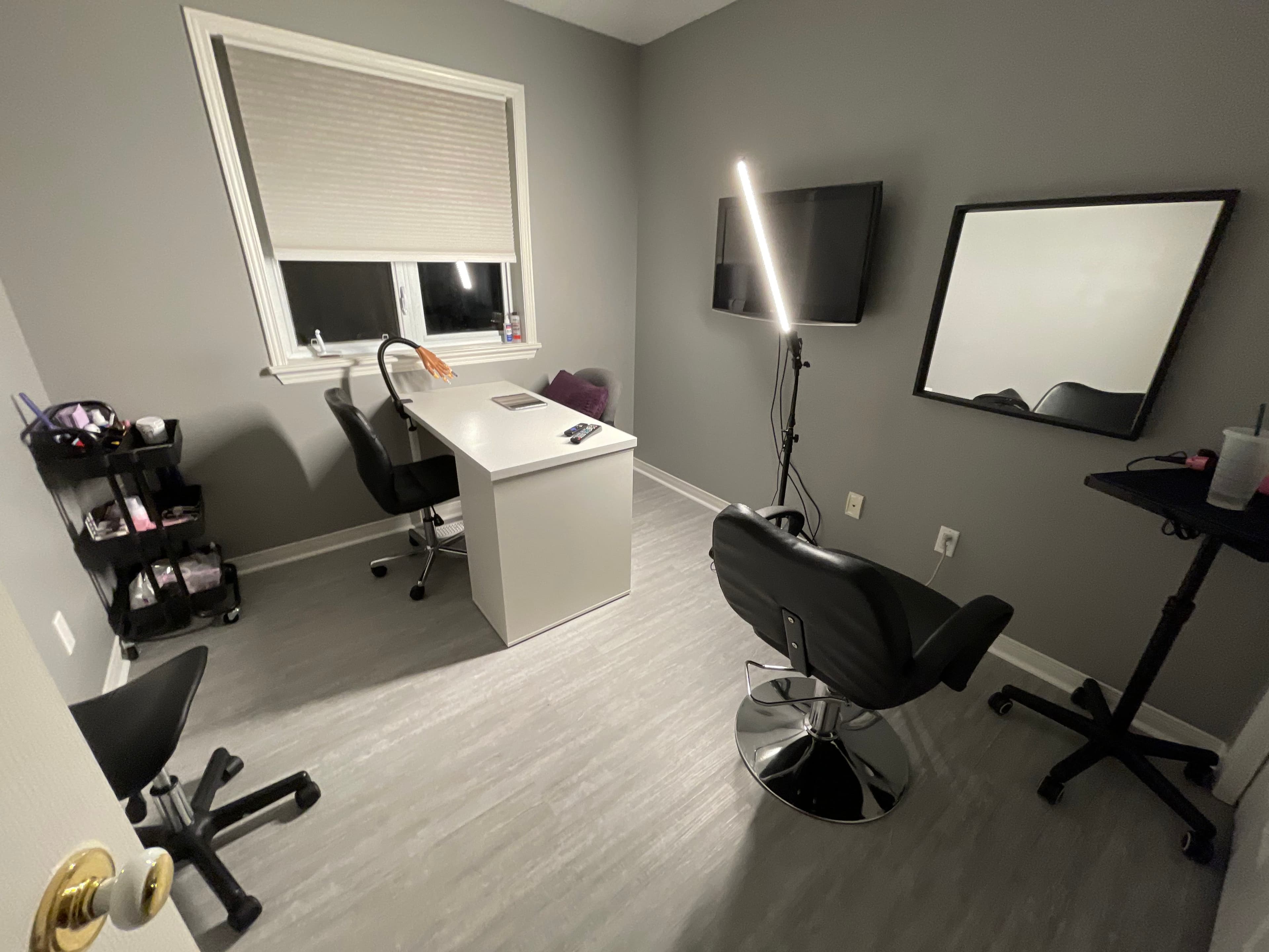 The studio room, with the client chair, work table, wall mirror and window.