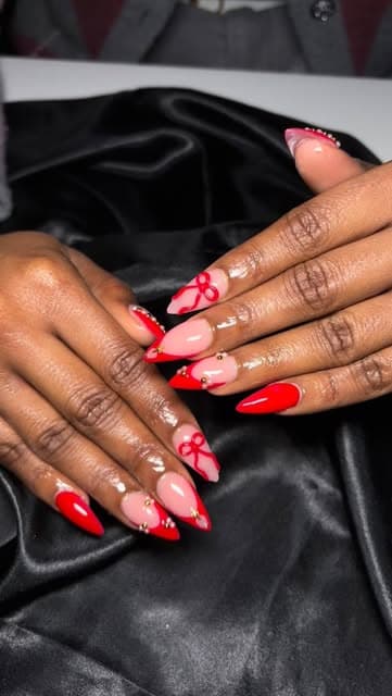 Red and orange nails with hand-painted floral art.